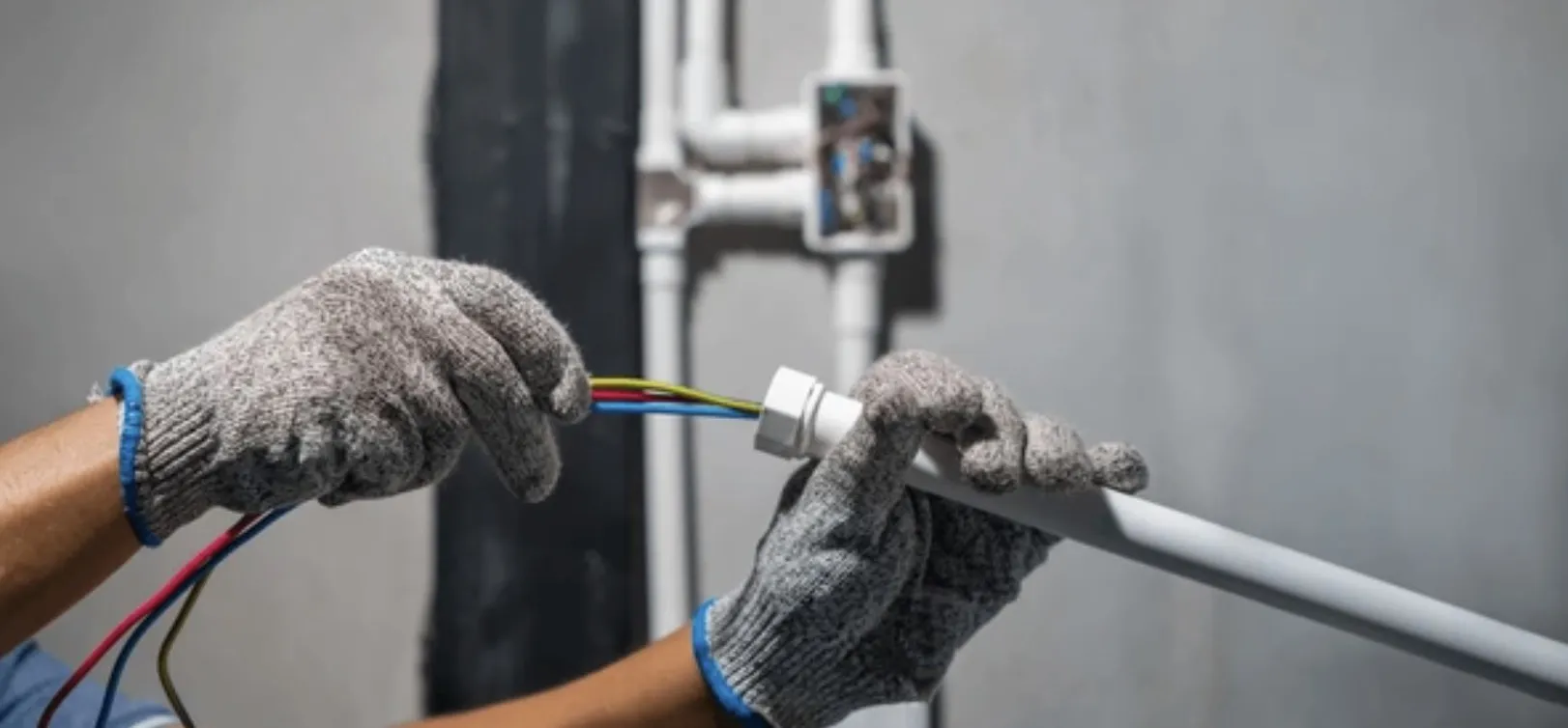 Elektricien trekt bedrading door een installatiebuis tijdens het aanleggen van elektra